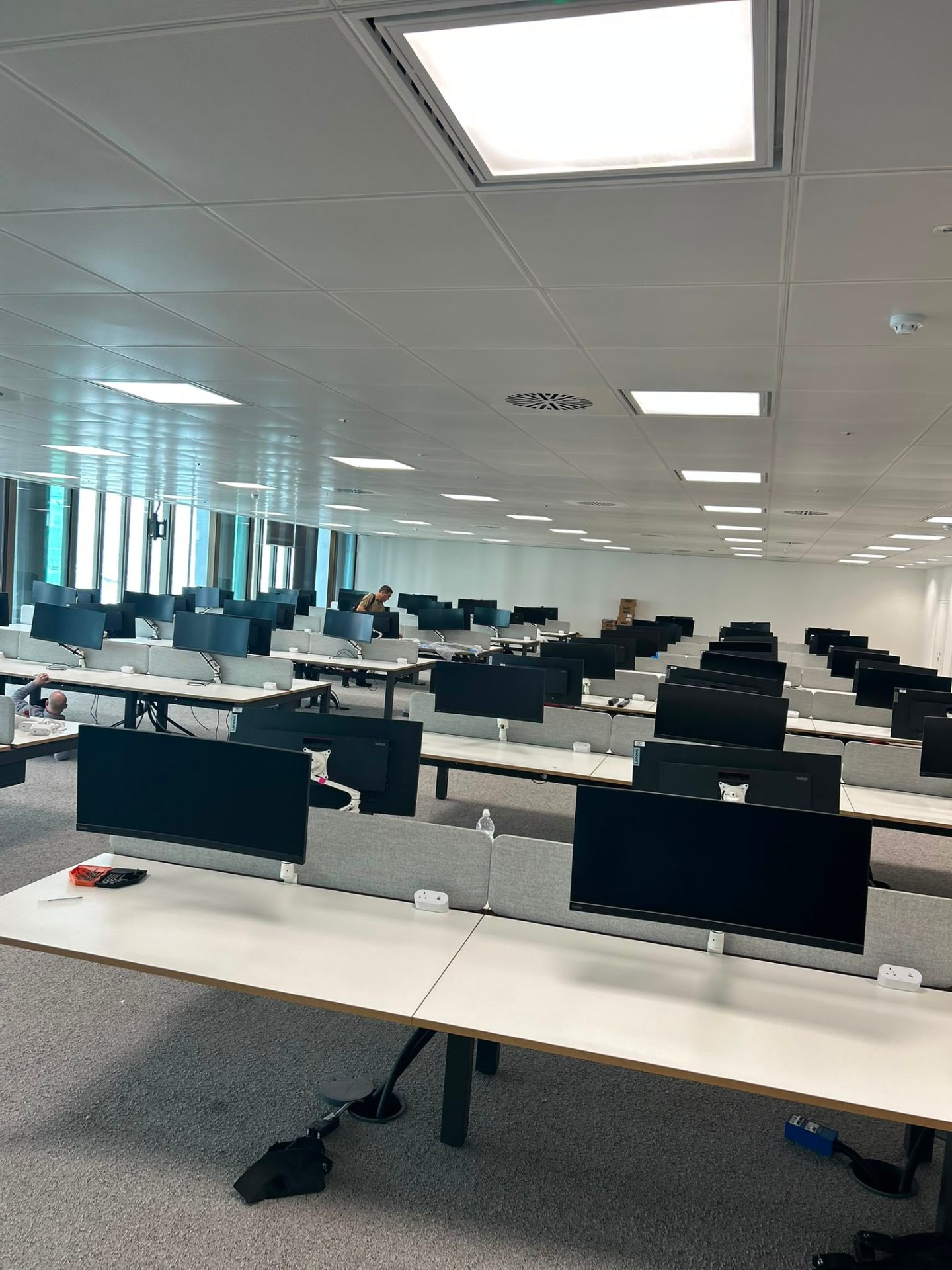 Bench desk installation with monitor arms and acoustic screens — London office